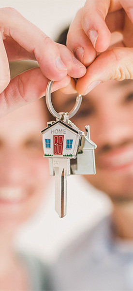 Photo of a young couple holding up a house shaped key ring with a key on it