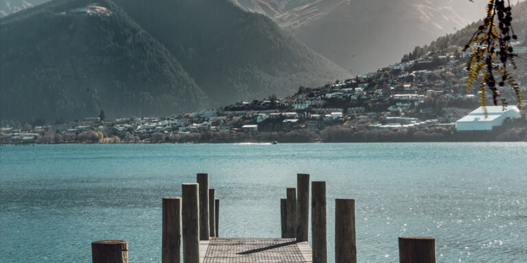Scenic view of Queenstown, New Zealand from a lakeside pier with mountains in the background, a popular destination for property investment under the Golden Visa program